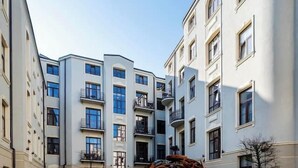 Ein Innenhof mit einem zentralen Zierrad, umgeben von mehrstöckigen Gebäuden mit Balkonen und Blumentöpfen.