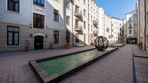 Ein Innenhof mit Swimmingpool, Kübelpflanzen und einer kugelförmigen Skulptur.
