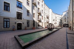 A courtyard with a swimming pool, potted plants, and a spherical sculpture. - Piotrkowska Apt - AC, Top Location - by Rentujemy (Łódź)