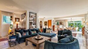 Een ruime woonkamer met een zithoek, een salontafel en een eethoek met stoelen en een tafel.