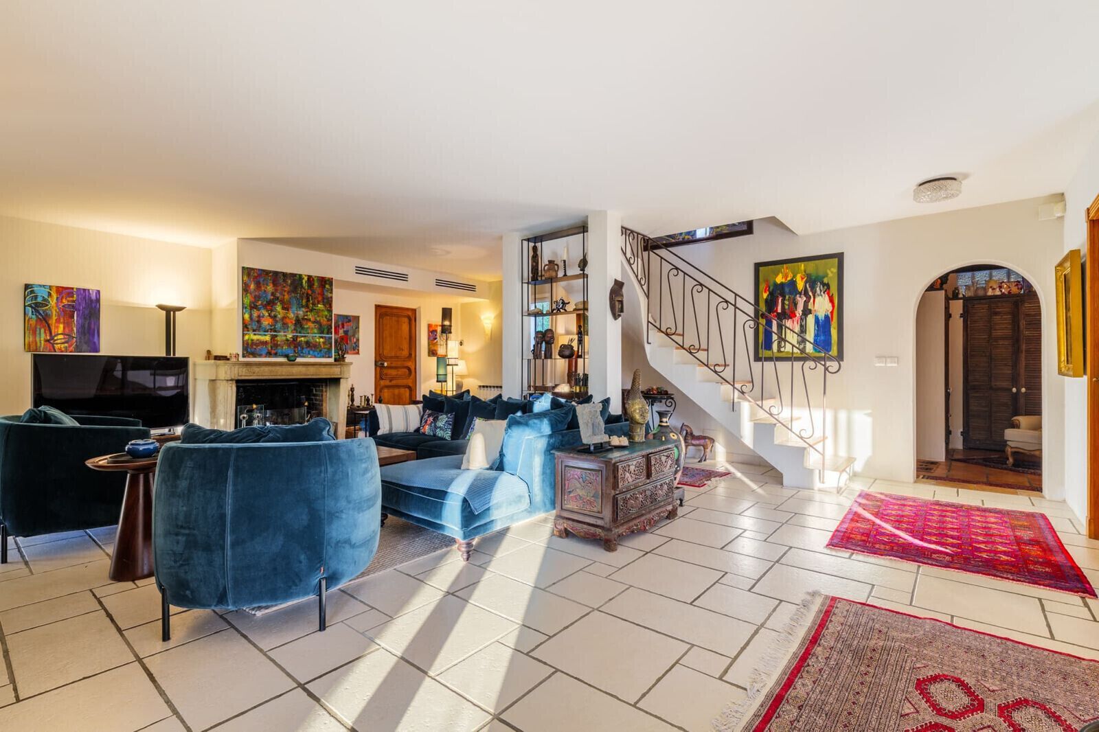 Ein Wohnzimmer mit Sofa, Fernseher, Kamin, Treppe und Kunstwerken.