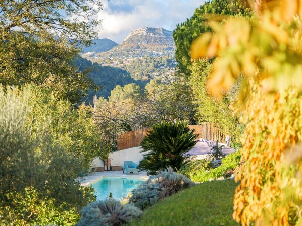 A pool surrounded by lush greenery and a mountainous backdrop. - Beatrice, villa with pool and view over St Paul de Vence village (Saint Paul de Vence)
