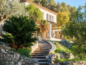 A stone staircase leading to a building with a tiled roof, surrounded by lush greenery and trees. - Beatrice, villa with pool and view over St Paul de Vence village (Saint Paul de Vence)