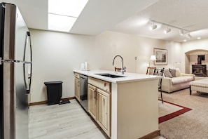 A modern kitchen with a built-in dishwasher, a central island, and a dining area with a sofa and table. - Ski in Ski out, Hot Tub, Perfect Mountain Getaway FP219 (Copper Mountain)