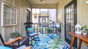 Eine überdachte Veranda mit Deckenventilator, einem gemusterten Boden und Blick auf den Garten.