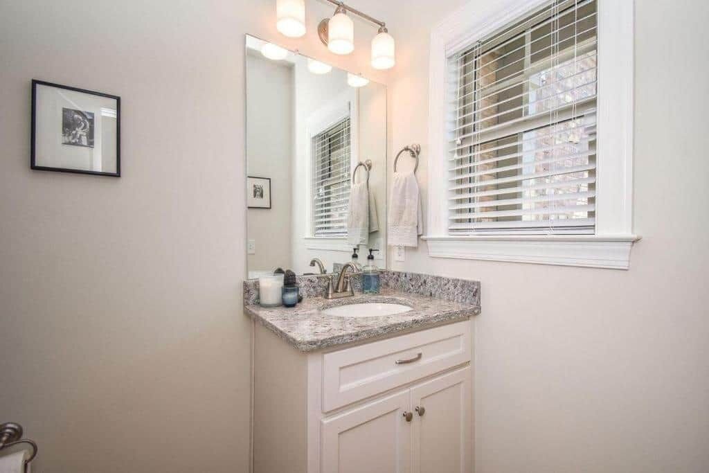 A bathroom with a sink, mirror, towel rack, and a framed picture on the wall.