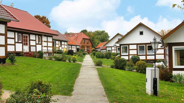 A row of traditional half-timbered houses with a central pathway leading to a distant building. - Feriendorf an der Ostsee, Wohlenberg (Klütz)