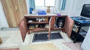 Une cuisine compacte équipée d’une cuisinière intégrée, d’un évier et d’un meuble en bois doté d’une étagère coulissante.