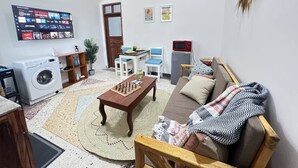 Un salon comprenant un lave-linge, un téléviseur fixé au mur, un coin repas et un canapé.