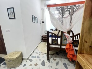 Une chambre à coucher comprenant un lit, une table de chevet, une lampe, un panier en osier et un mur orné de tableaux.
