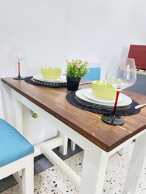 Une table à manger avec des bols verts, une plante en pot et des verres à vin.