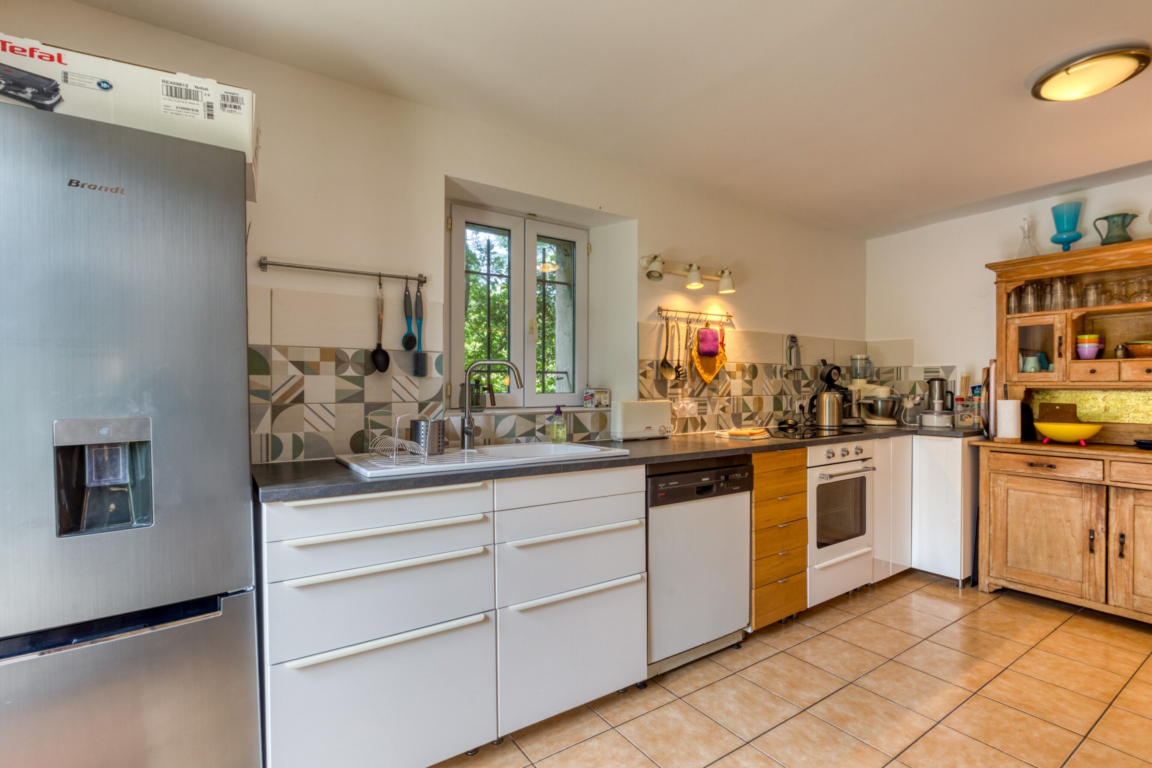 A modern kitchen with stainless steel appliances, a tiled backsplash, and wooden cabinets.