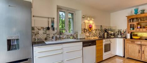 A modern kitchen with stainless steel appliances, a tiled backsplash, and wooden cabinets.