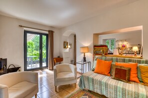 A room with a sofa, armchair, and a dining area with a table and chairs. - Holiday Home “Le Moulin de Mirande” with Terrace, Private Garden & Wi-Fi (La Tour-sur-Orb)