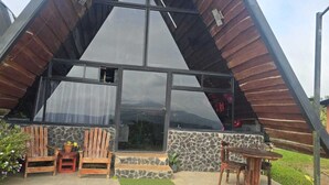 Un bâtiment triangulaire doté d’une façade en verre, de chaises en bois et d’un mur en pierre.