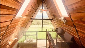 Une cabane en bois dotée d’un toit en verre, d’un coin repas et offrant une vue sur l’extérieur.