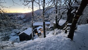 Un pueblo cubierto de nieve con edificios tradicionales, un muro de piedra y una vista de montañas distantes.