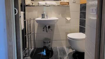 Un baño moderno con ducha, lavamanos e inodoro.