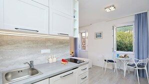 A modern kitchen with a sink, cabinets, and a dining area with chairs and a table. - Sophie 1 - Old Town Heritage Suite (Dubrovnik)