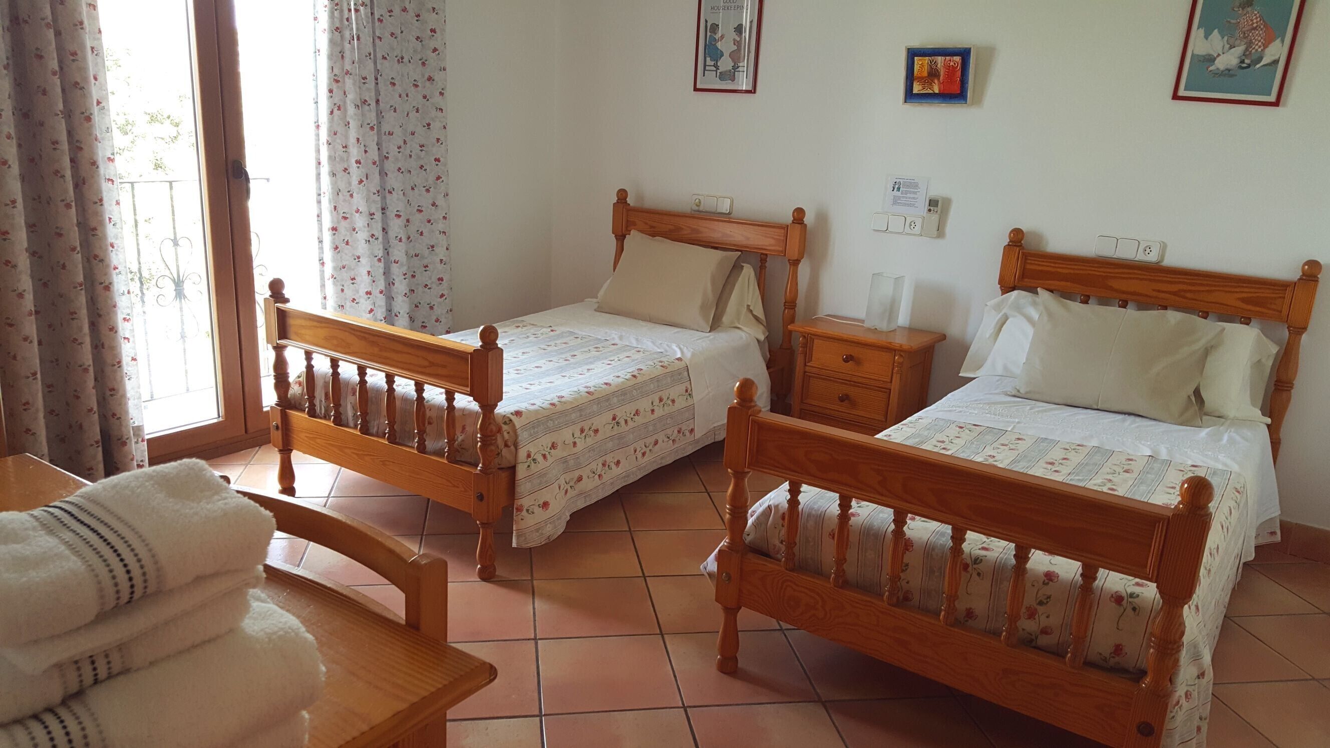 Una habitación con dos camas de madera, una mesa de madera y una silla.