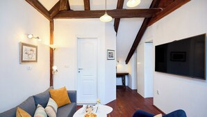 Un salon avec un canapé, une table basse et un téléviseur fixé au mur.