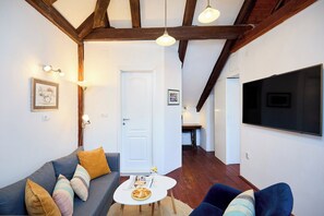 Ein Wohnzimmer mit einer Couch, einem Couchtisch und einem an der Wand befestigten Fernseher.
