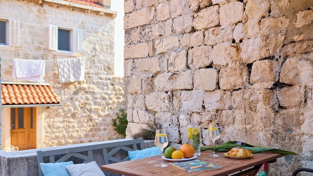Une table en bois sur laquelle se trouvent une assiette de fruits, un verre de vin et une bouteille d’eau.