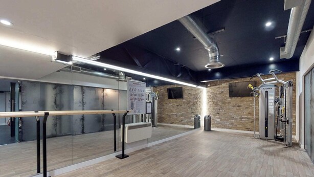 A gym with a mirrored wall, exercise equipment, and a wooden floor. - Student Only The Bridge Phase II (Newcastle-upon-Tyne)
