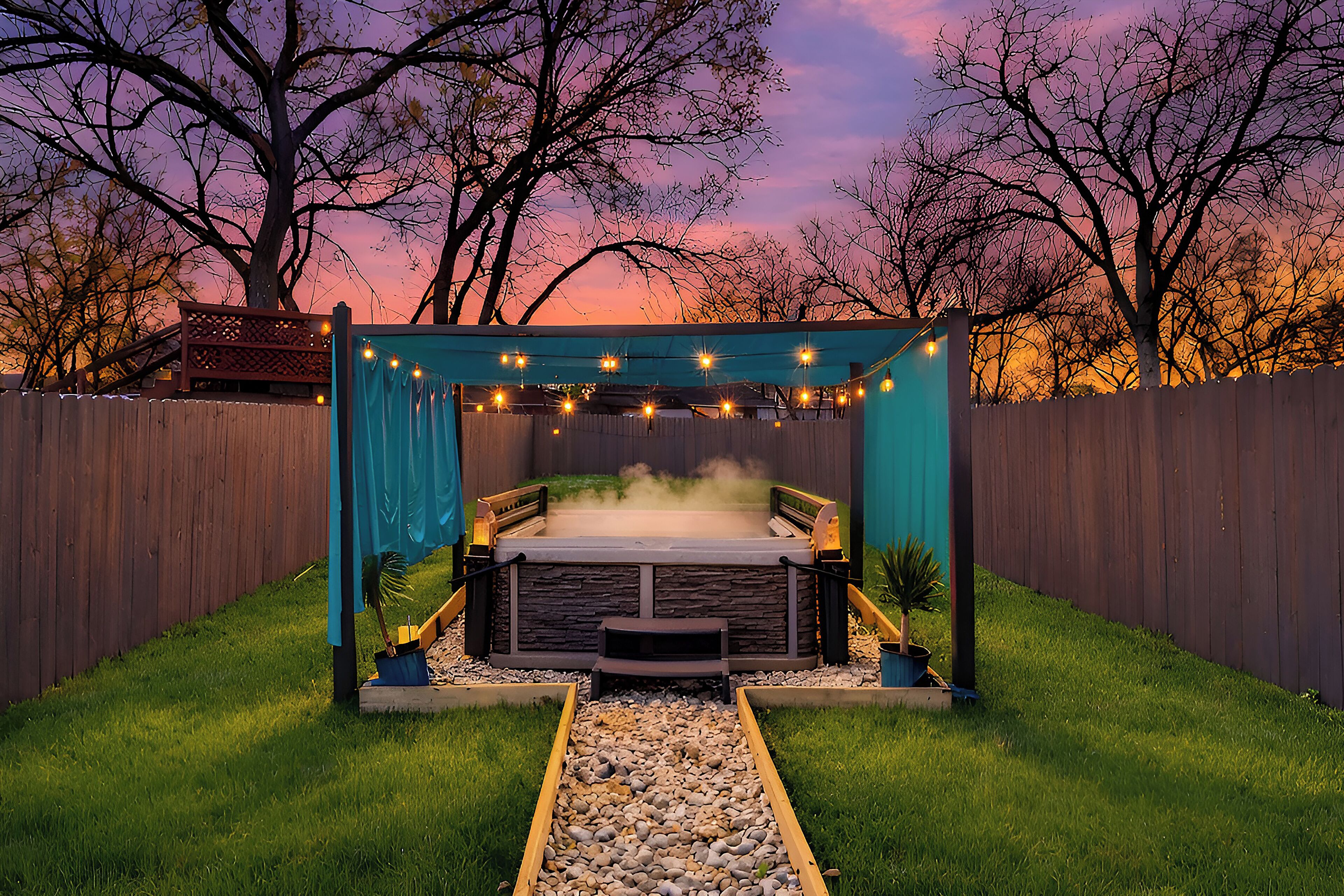 A hot tub with a stone surround, a wooden deck, and a string of lights.