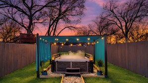 Ein Whirlpool mit Steinfassung, einer Holzterrasse und einer Lichterkette.