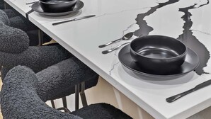 Eine moderne Küche mit weißem Marmor-Arbeitsplatz, schwarzen Schüsseln und silbernem Besteck.