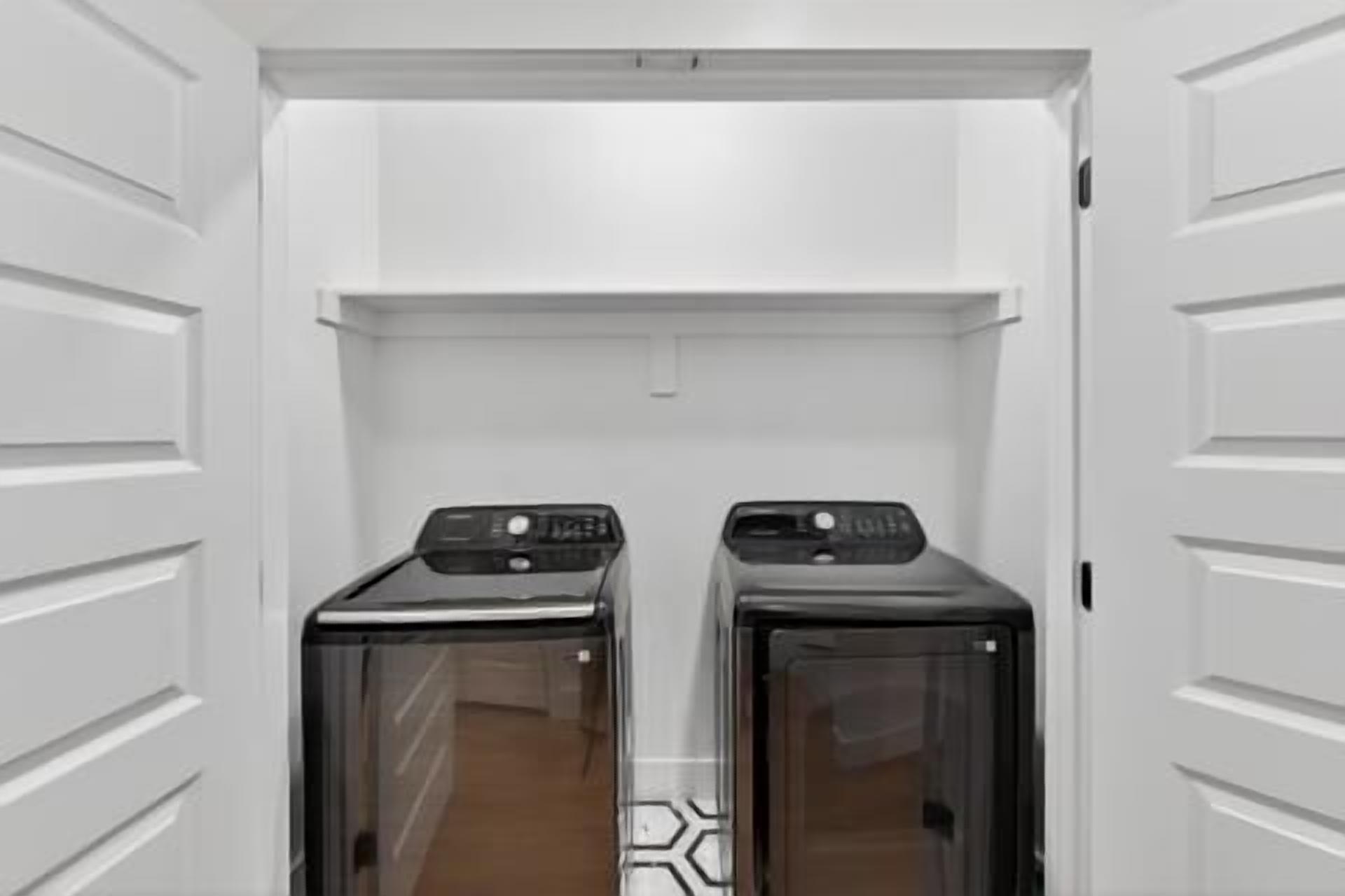A laundry room with two dryers and a white door.