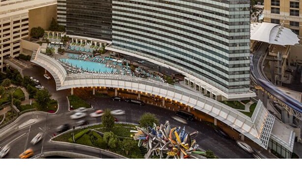 Un hôtel de grande hauteur doté d’une façade en verre incurvée, d’une piscine sur le toit et offrant une vue sur le paysage urbain environnant.