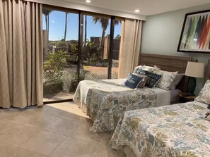 A hotel room with two beds, large windows with curtains, a view of palm trees, and a framed picture on the wall. - SpaceX Launches and Fun Filled Family Beach Days - 1st Floor 2BR/2BA Condo (South Padre Island)
