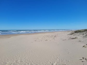 A wide sandy beach with gentle waves and a clear blue sky. - SpaceX Launches and Fun Filled Family Beach Days - 1st Floor 2BR/2BA Condo (South Padre Island)