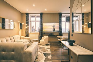 A modern living room with a sofa, armchair, and a dining area with a TV. - "Pearl" panoramic view (Lons-le-Saunier)