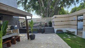 Une terrasse avec un sol en pierre, des sièges d’extérieur, des plantes en pot et un espace abrité offrant une vue sur le paysage environnant.