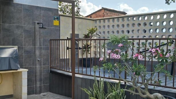 Un espace extérieur aménagé en patio, avec un sol en pierre, une porte en métal et des plantes en pot.