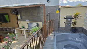 Un espace bien-être comprenant un jacuzzi, un petit coin salon et un téléviseur fixé au mur.