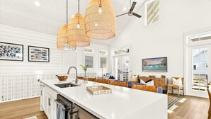 A spacious kitchen with a large island, pendant lighting, and a view to the living area. - Sol Seekers 109 PLA (Port Aransas)