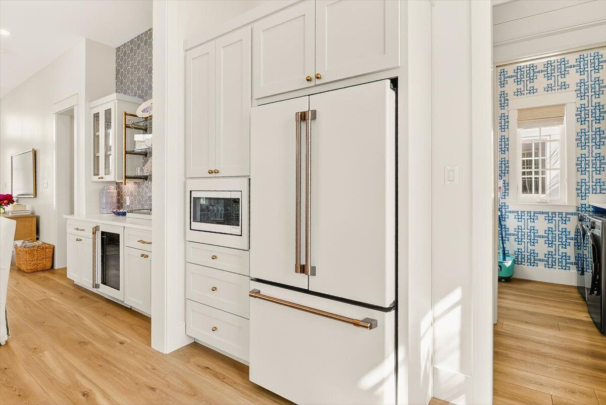 A modern kitchen with white cabinetry, a built-in oven, and a large refrigerator.