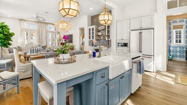 Una cocina moderna con una isla grande, muebles blancos y detalles en azul.