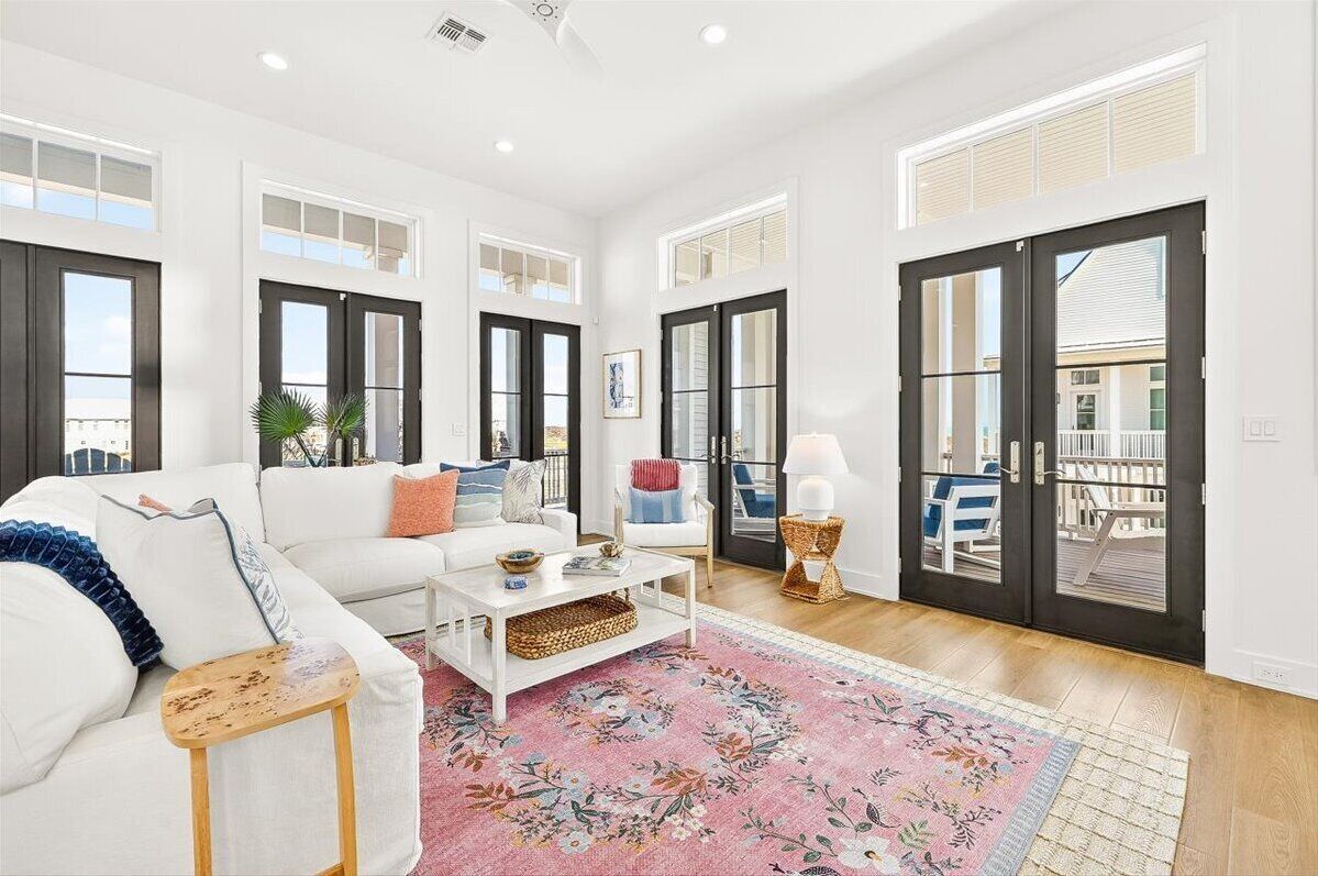 A spacious living room with a white sofa, a coffee table, and a large window.