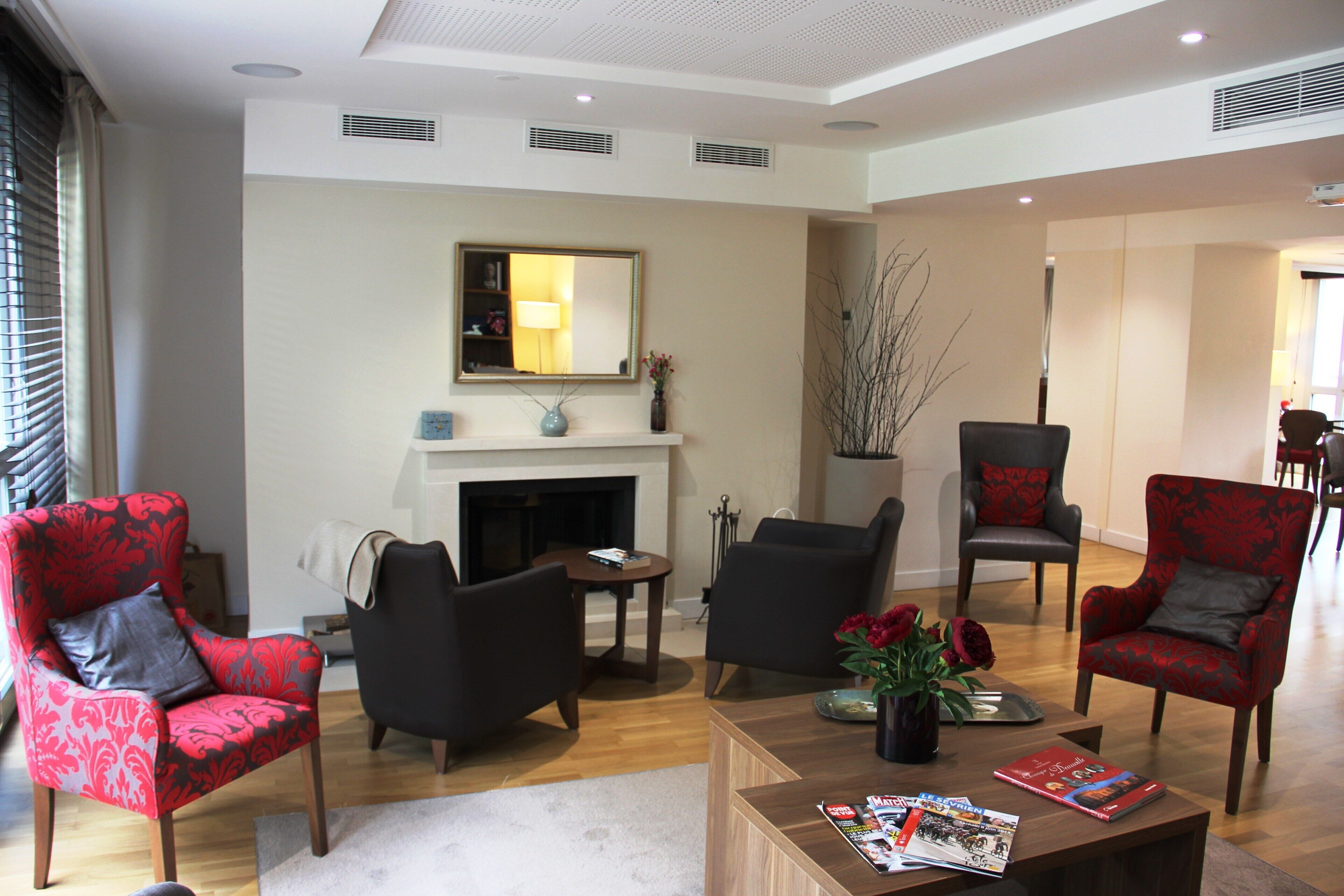 Un salon moderne avec une cheminée, plusieurs fauteuils, une table basse et un grand miroir au mur.
