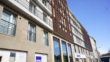 Un edificio de varios pisos con amplios ventanales, un llamativo diseño de paneles verticales de madera y un escaparate con letrero.