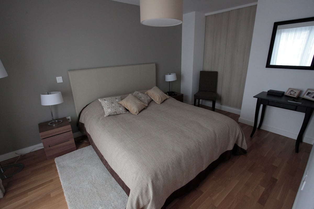 Une chambre à coucher avec un grand lit, des tables de chevet, une chaise, un bureau et un miroir.