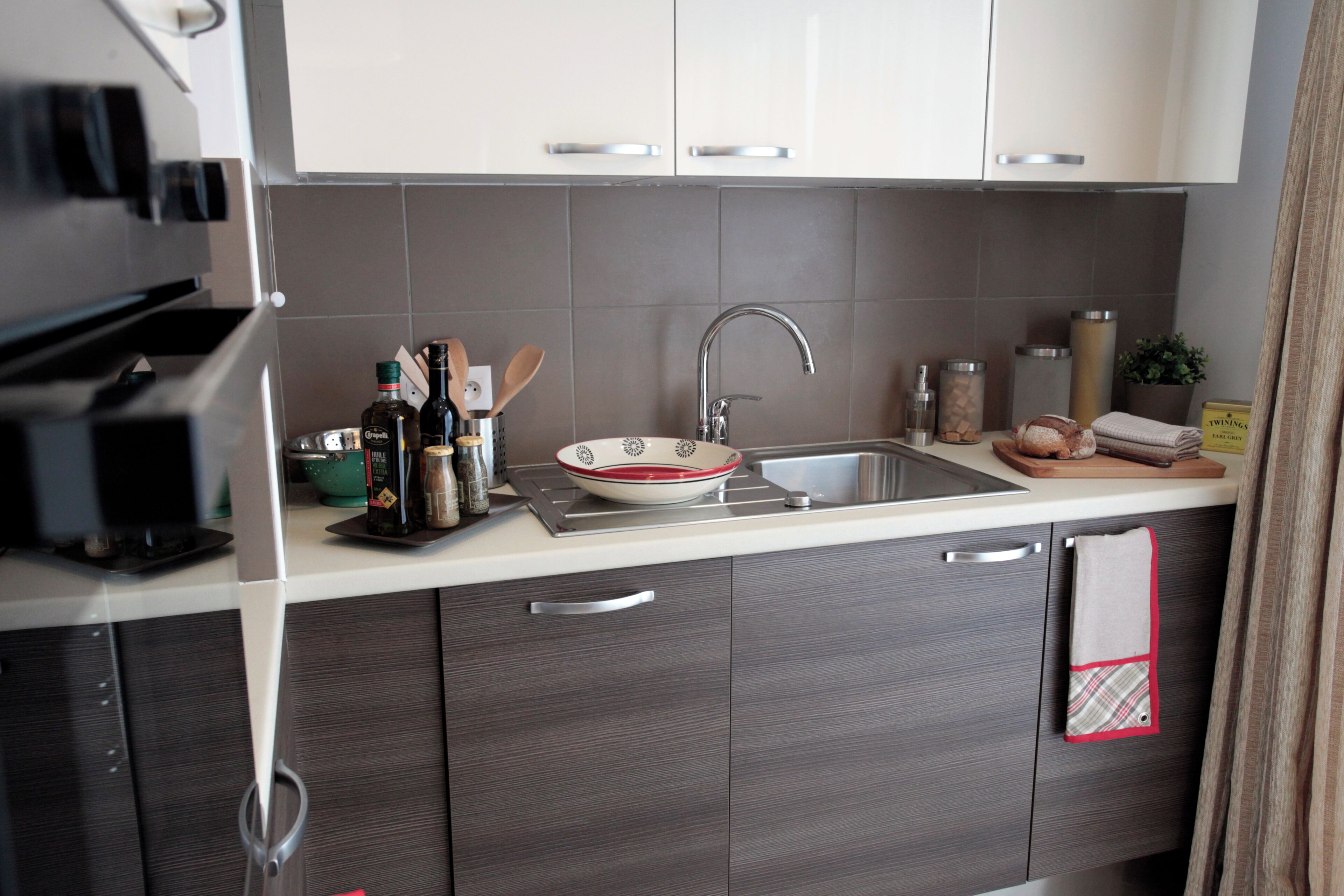 Een moderne keuken met een roestvrijstalen spoelbak, een magnetron en een inbouwoven.
