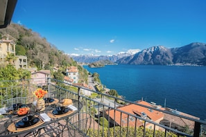 A terrace with dining setup overlooking a lake and mountains. - Alba on Lake Como (Sala Comacina)