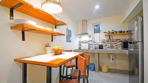A kitchen with wooden shelves, a dining table, chairs, and a refrigerator. - Poolside Retreat  Lounge Parking Near Downtown (La Paz)