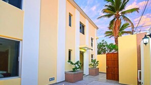 A modern building with a courtyard, a wooden gate, and a palm tree. - Poolside Retreat  Lounge Parking Near Downtown (La Paz)